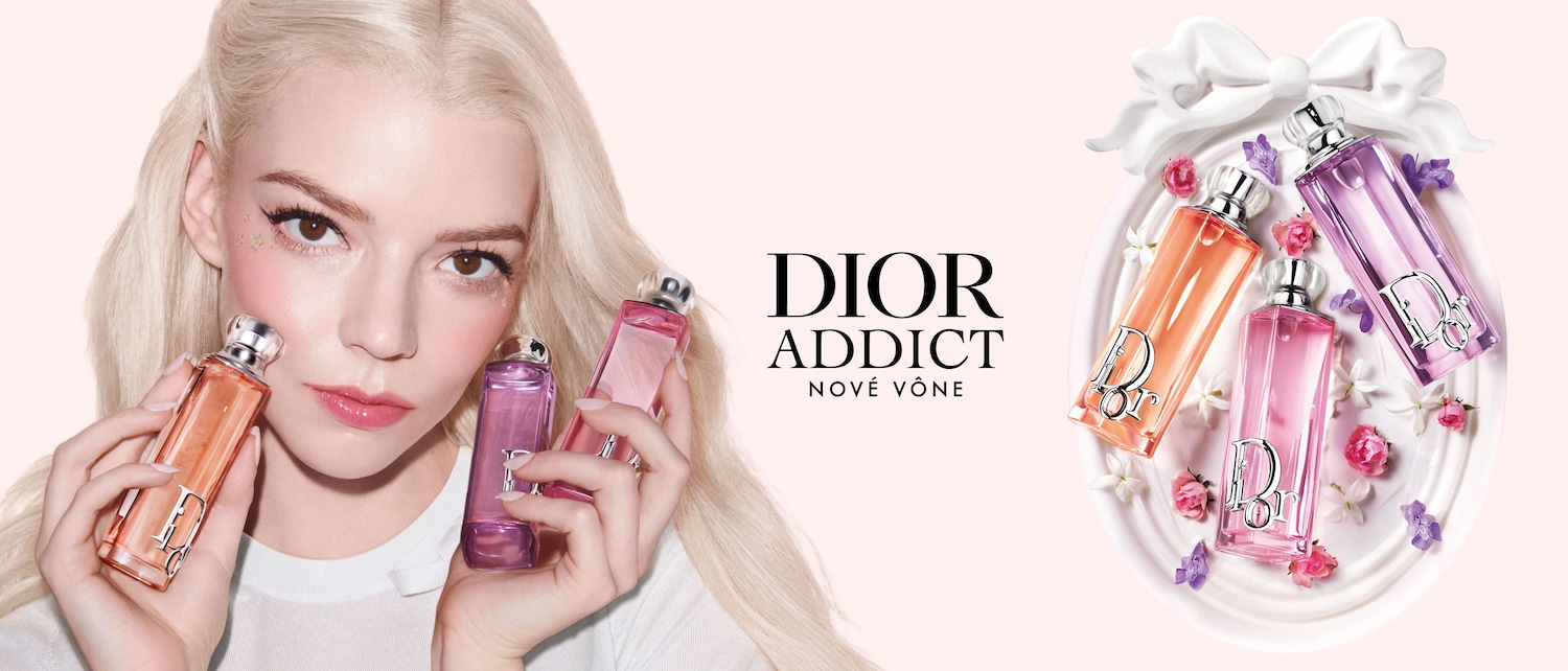 Na obrázku je Anya Taylor-Joy, ktorá drží v rukách tri flakóny vône Dior Addict v odtieňoch oranžovej, ružovej a fialovej, pričom v pozadí je aranžmán s kvetmi a flakónmi na ozdobnom podnose.