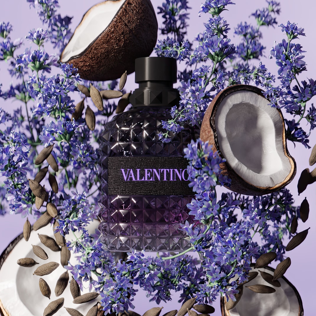 Fľaša Valentino obklopená kokosom, mandľami a fialovými kvetmi vytvára zmyselnú kompozíciu.