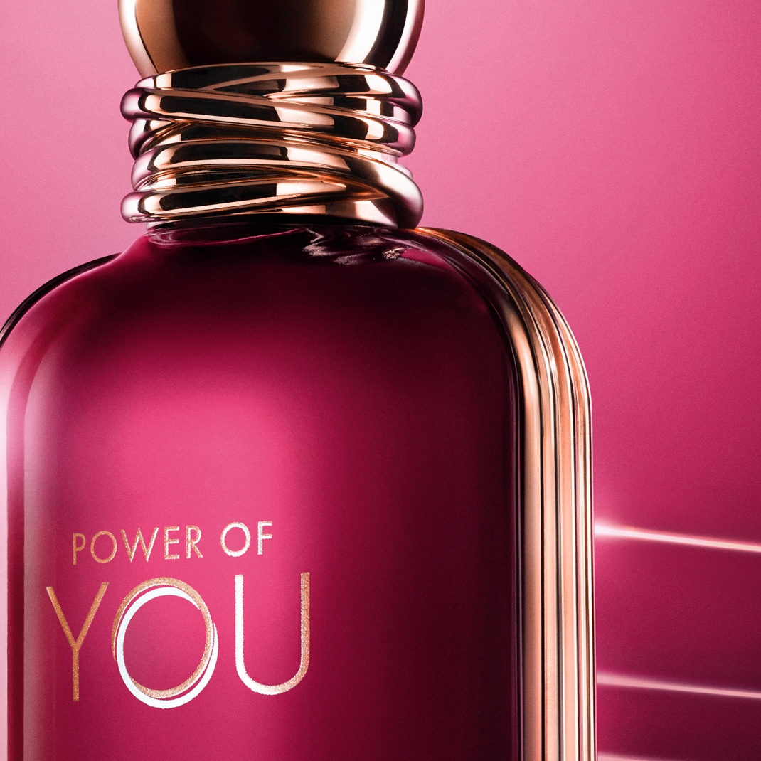 Detailný záber na fľašu parfému s nápisom "POWER OF YOU" na sýto ružovom pozadí, doplnený o zlaté akcenty na hrdle a okrajoch.
