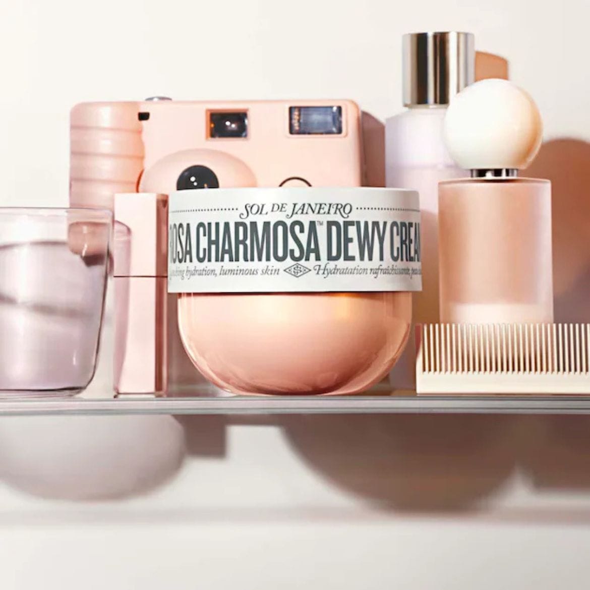 Ružový krém Sol de Janeiro Rosa Charmosa Dewy Cream sľubuje hydratáciu pre žiarivú pleť, doplnený o ružový fotoaparát, parfum a hrebeň.