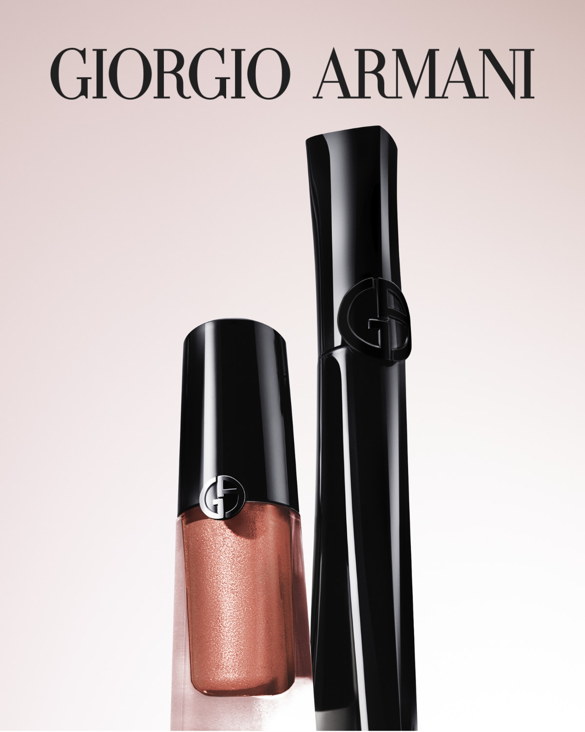 Dve fľaštičky Giorgio Armani, jedna s lesklým hnedým tekutým očným tieňom a druhá s čiernou riasenkou, sú zobrazené na svetloružovom pozadí.